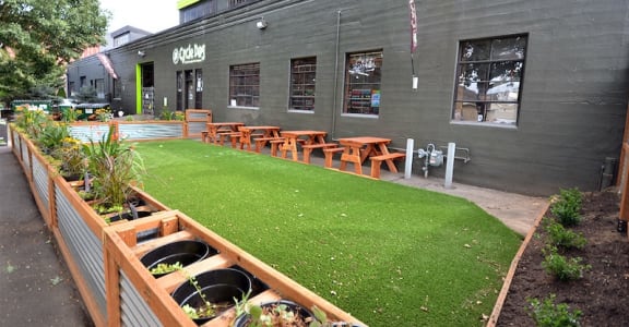 the outside of the restaurant with a lawn and tables