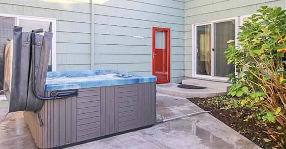 A hot tub sits on a patio in front of a house.