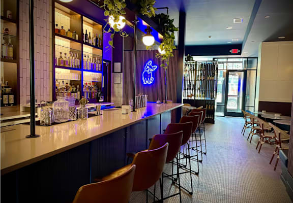 A bar with a row of chairs in front of it.