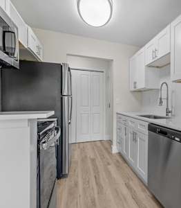 A kitchen with white cabinets and a black refrigerator.