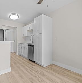 A kitchen with white cabinets and a wooden floor.