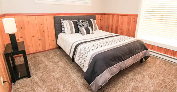 A bedroom with a bed, nightstand, and window.
