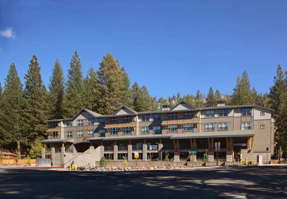 A large building with a balcony on the second floor is surrounded by trees.
