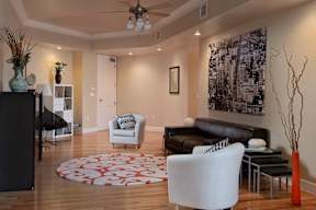 A spacious living room with a ceiling inlay, a ceiling fan, recessed lighting, hardwood style flooring, and access to the front door.