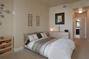 A bedroom with plush carpet flooring, high ceilings, natural light, and access to a private bathroom.