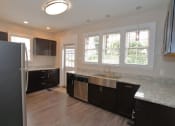 Thumbnail 7 of 8 - a kitchen with dark cabinets and a stainless steel sink