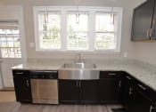 Thumbnail 8 of 8 - a kitchen with dark cabinets and a stainless steel sink