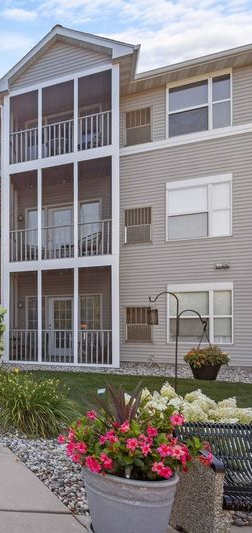 A wooden deck with a railing and a view of trees and a building in the background.