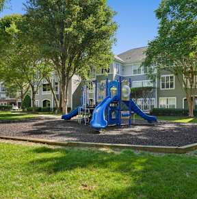 A playground with a blue slide in the middle of a grassy area.