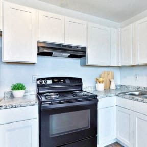 a kitchen with white cabinets and a black stove