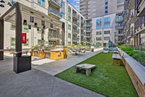 A modern outdoor seating area with a grassy lawn and concrete flooring.