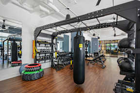 A gym with a punching bag, weights, and exercise equipment.