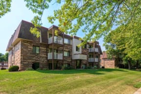 a large brick apartment building with green grass and trees