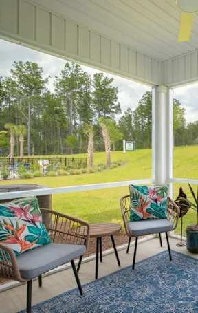 A sunny day in a white-framed porch with a table and chairs.