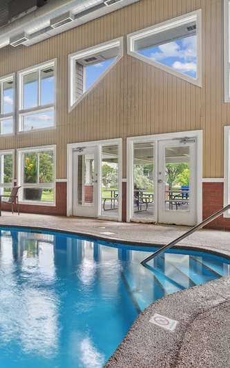 A large indoor swimming pool with a sunny day outside.