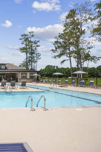 a swimming pool with chairs and a building in the background