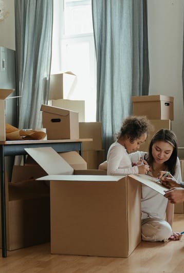 a family sitting on the floor surrounded by cardboard boxes and a laptop