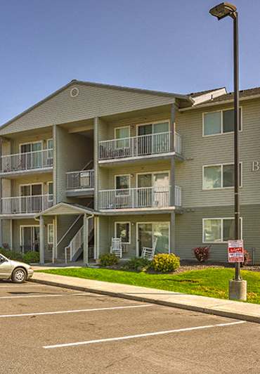 a swimming pool with chairs in front of an apartment building at FOREST CREEK APARTMENTS, Washington, 99208
