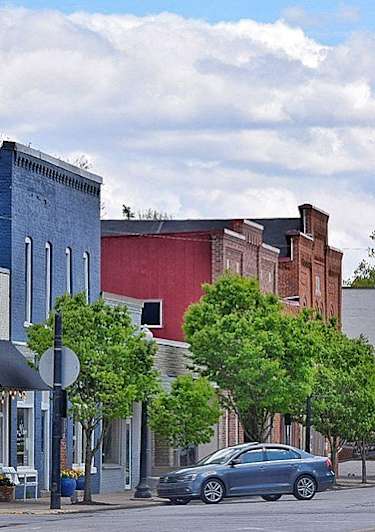 A street view of a town with a car parked on the side of the road.