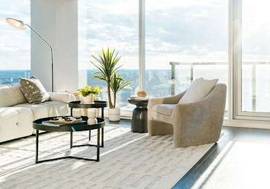 A living room with a white sofa, a black coffee table, and a large window with a view of the city.