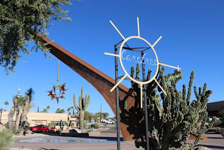 A sign for a place called Carefree is in front of a cactus.