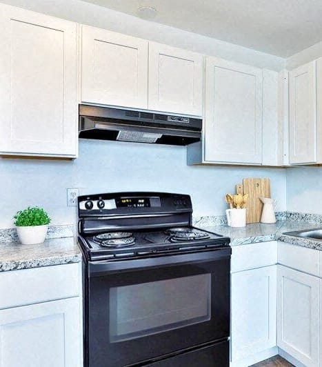 a kitchen with white cabinets and a black stove