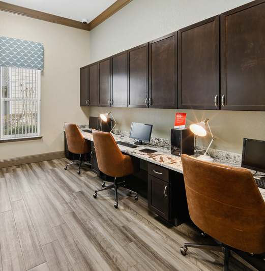 A room with brown chairs and a desk with a computer.