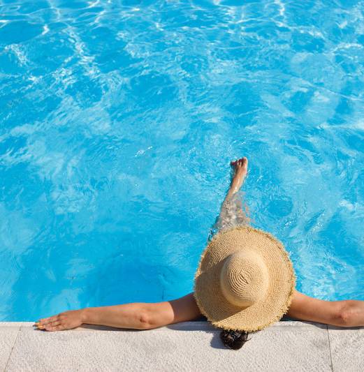 A person in a straw hat is relaxing in a pool.