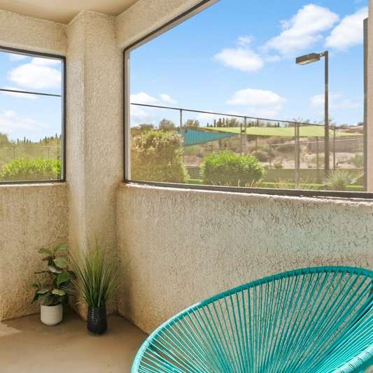 A balcony with a chair and a potted plant.