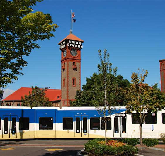 A train is parked in front of a building with a clock tower.