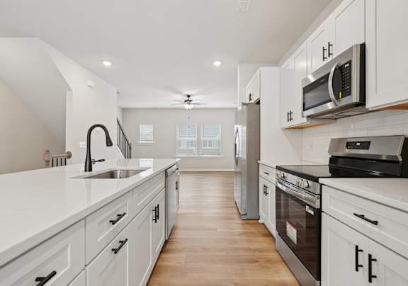 A modern kitchen with white cabinets and stainless steel appliances.