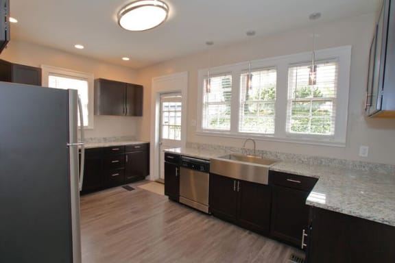 a kitchen with dark cabinets and a stainless steel sink