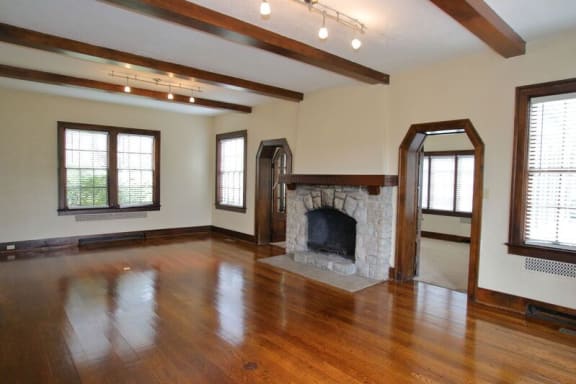 an empty living room with wood floors and a stone fireplace