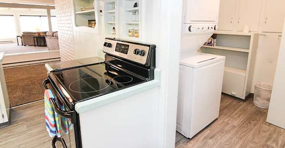 A white kitchen with a black stove top oven.