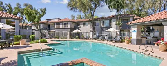 A swimming pool surrounded by a patio with chairs and umbrellas.