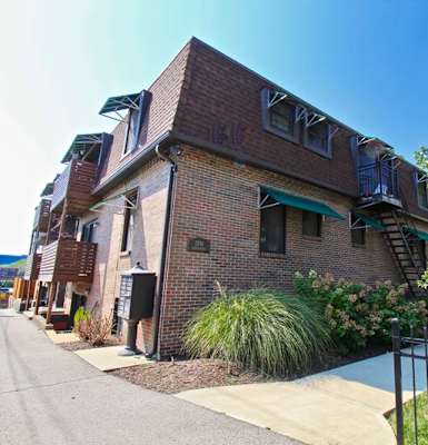 A brick building with a green awning and a black fence.