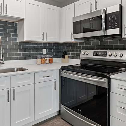 a kitchen with white cabinets and black appliances