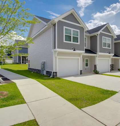 A row of houses with a sidewalk in front.