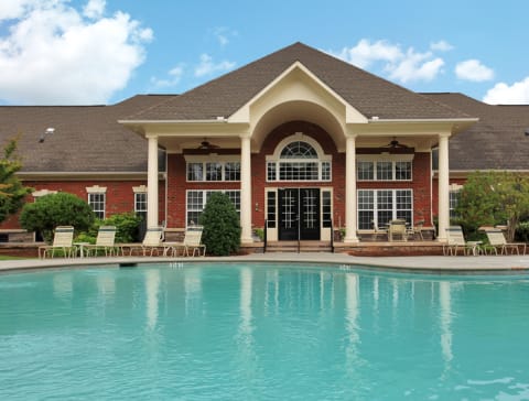 Clubhouse exterior with view of swimming pool and resort style lounge chairs