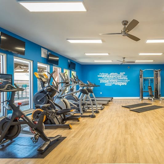 a gym with exercise equipment and a ceiling fan