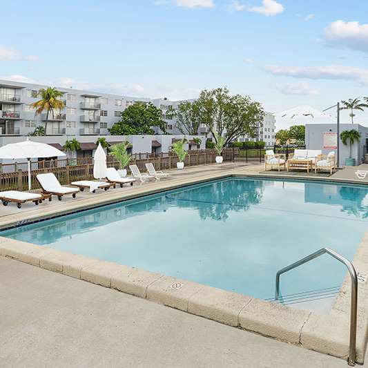 A large outdoor pool surrounded by a fence and chairs.