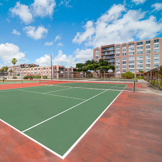 A large outdoor pool surrounded by a fence and chairs.