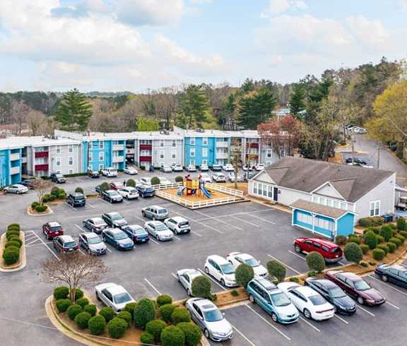 an aerial view of an apartment complex with parking lot and cars