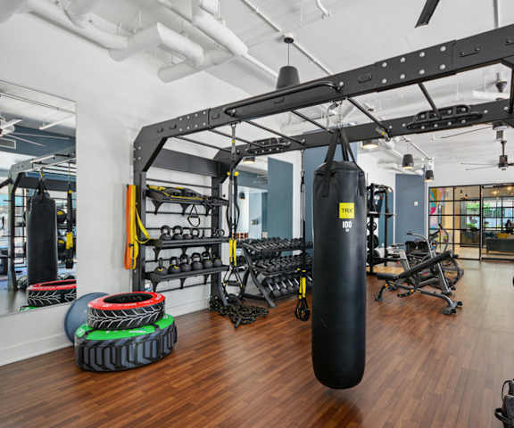 A gym with a punching bag, weights, and exercise equipment.