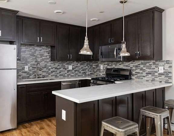 A kitchen with dark wood cabinets and a white counter.