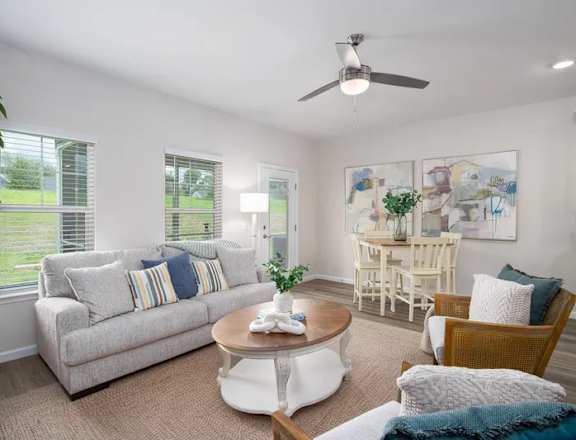 A living room with a couch, chairs, and a ceiling fan.
