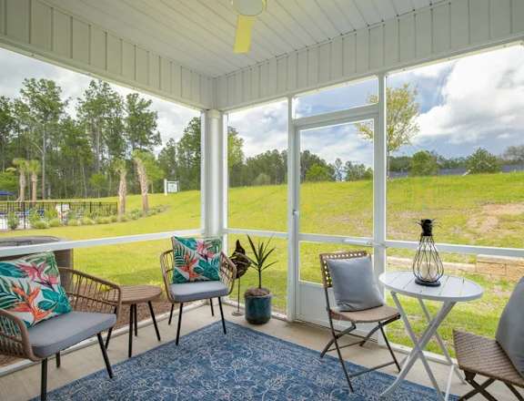 A sunny day in a white-framed porch with a table and chairs.