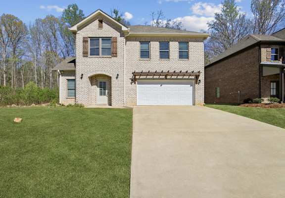 a white brick house with a driveway and a white garage door