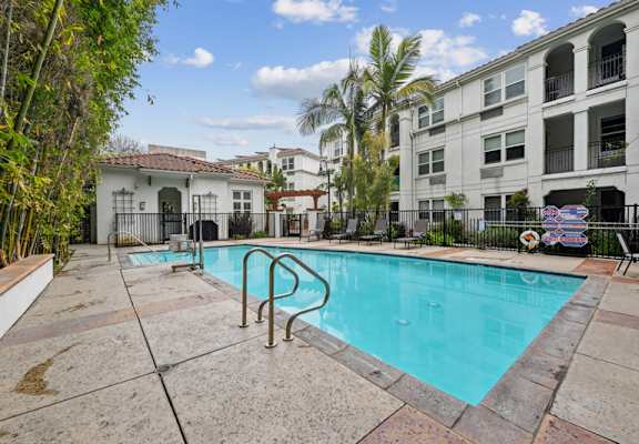 A swimming pool surrounded by a concrete patio and a black fence.