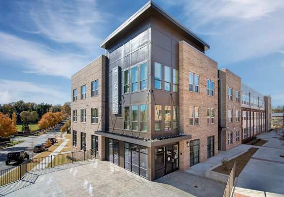 A modern building with a glass facade and a mix of brick and concrete materials.